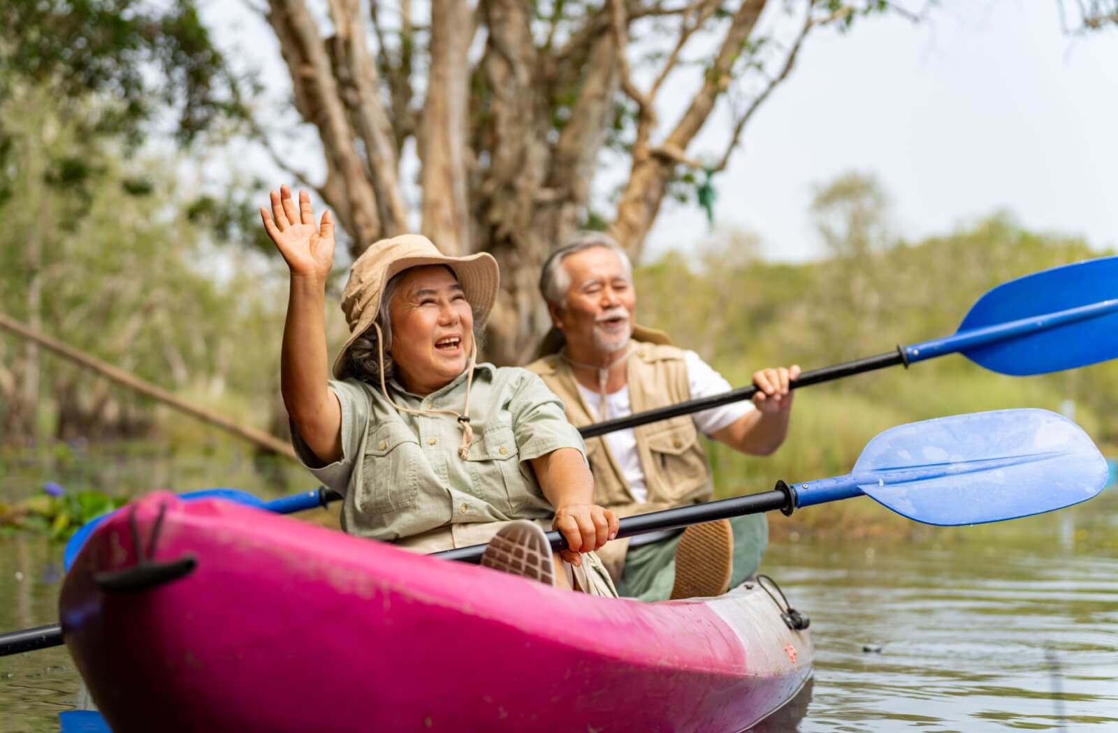 A happy senior couple enjoy paddling an inflatable canoe during a summer outing.