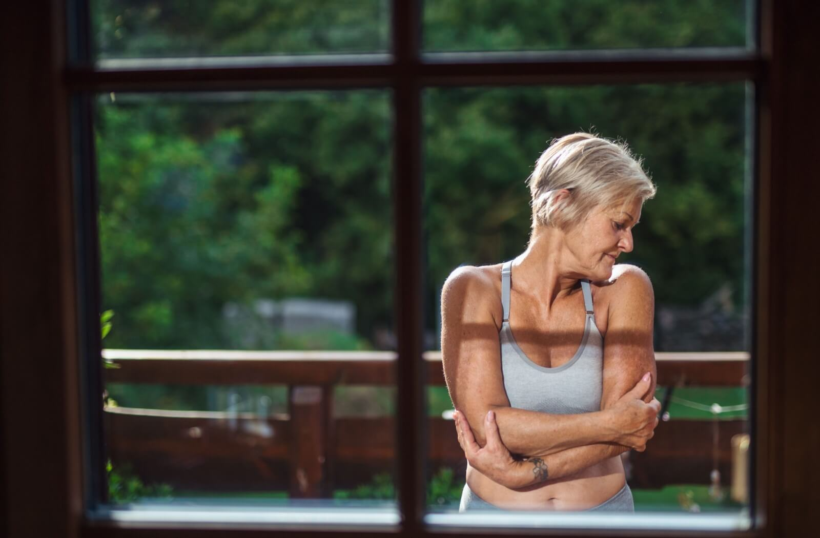 Person in a supportive sports bra standing near a window with natural light