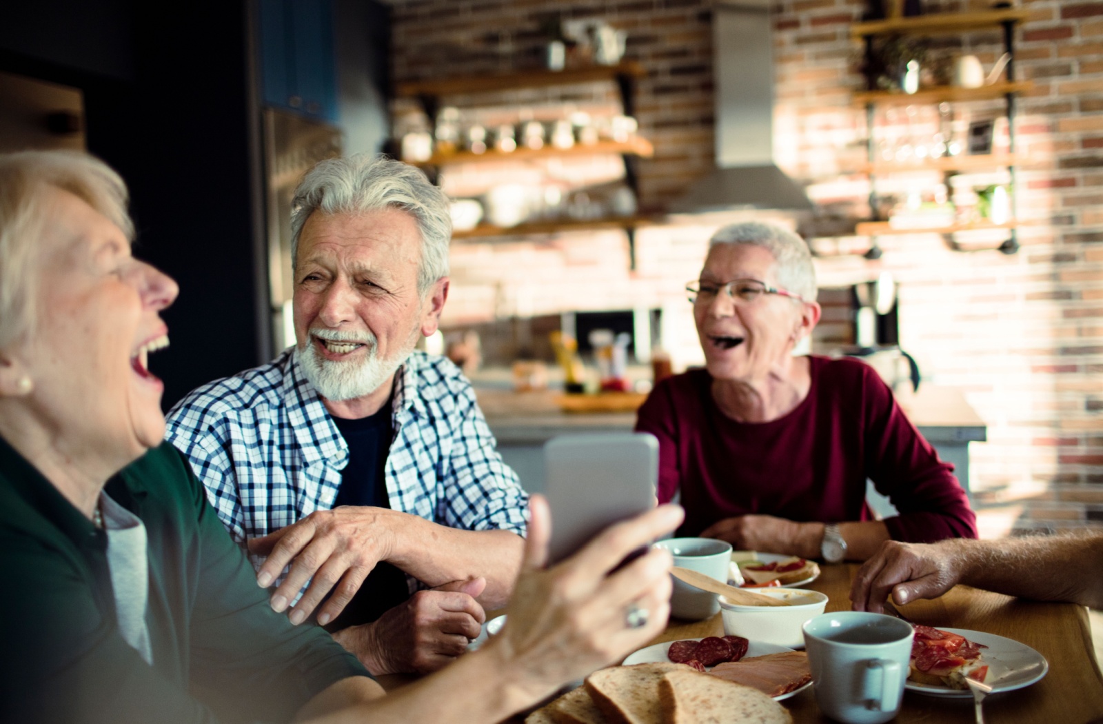 A group of senior friends laugh together over lunch.